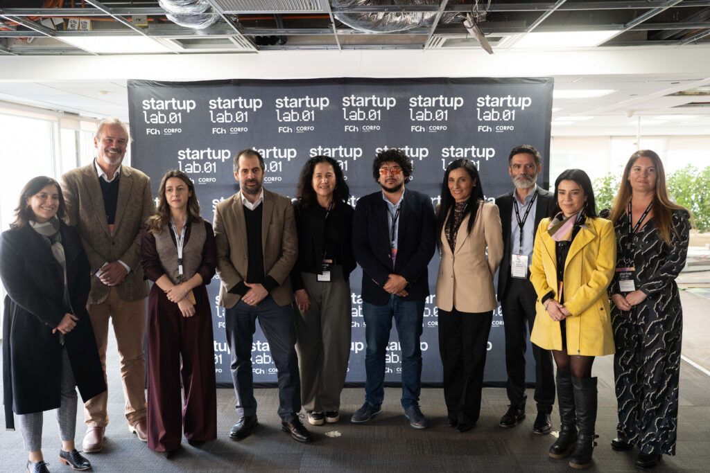 Un grupo de personas de pie frente a un banner, sonriendo y posando para la foto.
